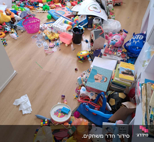 צעצועים וספרים מפוזרים על רצפת עץ בחדר ילדים